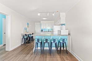 Cozinha moderna com armários brancos, bancada azul e banquetas.