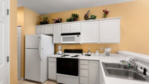 A compact kitchen with white cabinets, a refrigerator, a microwave, an oven, and a sink. - Escape to River Oaks | Golf, Beach & More Await! | RO 50B (Myrtle Beach)