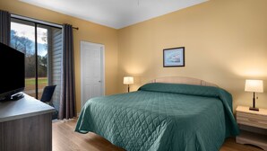 A bedroom with a bed, two bedside lamps, a TV on a desk, a door, and a window with curtains. - Escape to River Oaks | Golf, Beach & More Await! | RO 50B (Myrtle Beach)