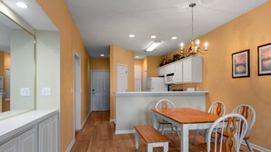 A kitchen with white cabinets, a wooden dining table, and a bench. - Escape to River Oaks | Golf, Beach & More Await! | RO 50B (Myrtle Beach)