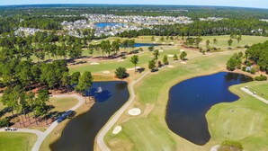 An aerial view of a golf course with multiple ponds, surrounded by residential areas and dense forests. - Myrtle Beach Fun | Golf & River Oaks Awaits You! | RO 5C (Myrtle Beach)