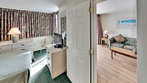 Ein Hotelzimmer mit Bett, Schreibtisch, Stuhl, Kommode, Fernseher und einer Sitzecke.