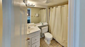 A compact bathroom with a sink, toilet, and shower curtain.