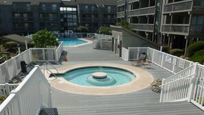 Un espace piscine aménagé sur le toit, avec un jacuzzi circulaire, entouré de rampes blanches et de chaises longues.