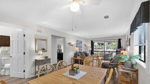 Un vaste espace dédié à la salle à manger, avec une table en bois, des chaises et un ventilateur de plafond.