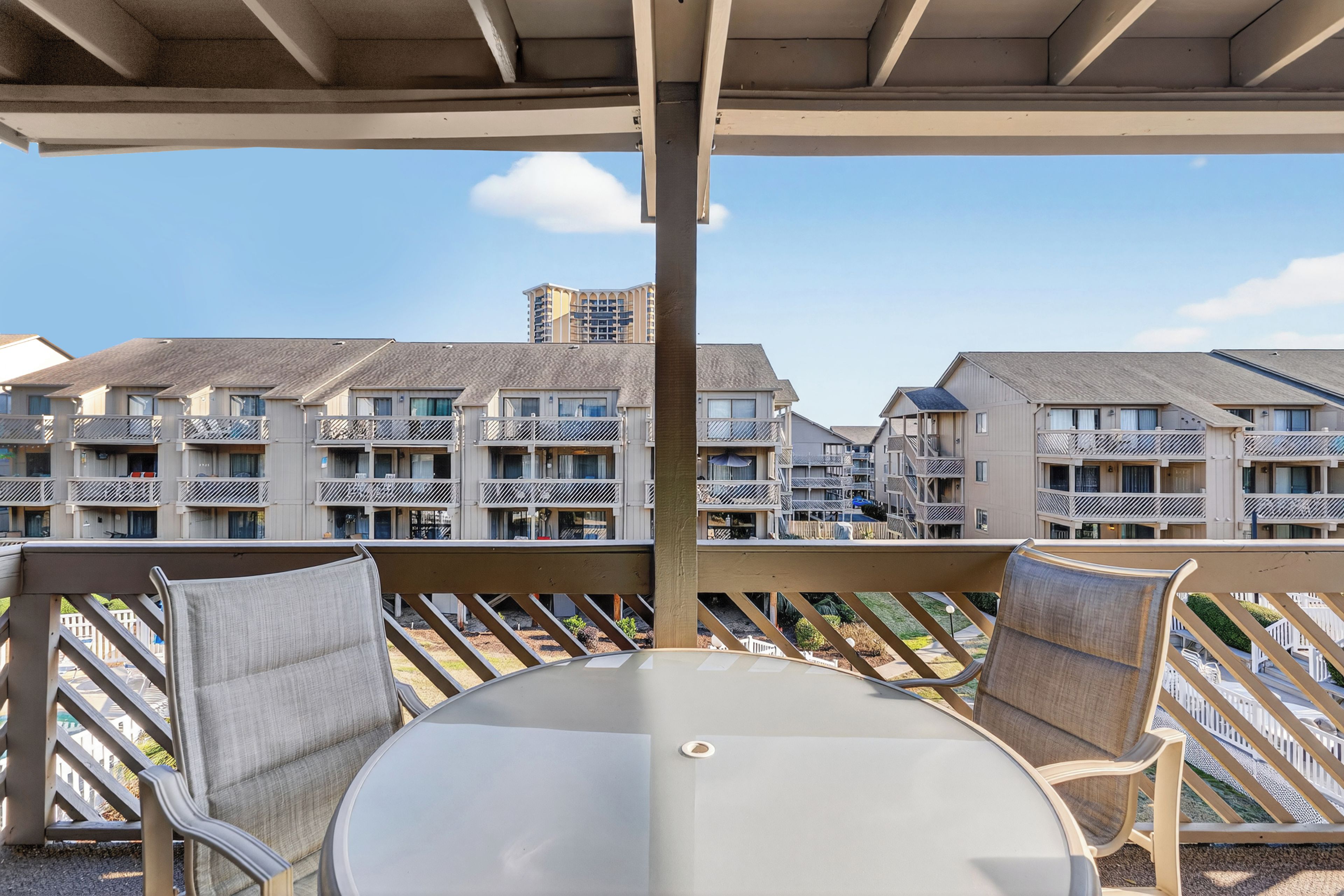 Ein Balkon mit Tisch und Stühlen, der auf eine Reihe mehrstöckiger Gebäude mit Balkonen blickt.