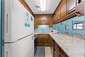 A compact kitchen with wooden cabinets, a white refrigerator, a sink, and a microwave.
