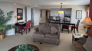 A living room with a sofa, a coffee table, and a dining area with chairs and a table.