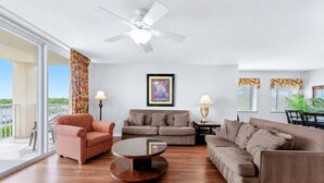 Ein großzügiges Wohnzimmer mit Deckenventilator, zwei Sofas, einem Couchtisch und einem großen Fenster mit Blick.