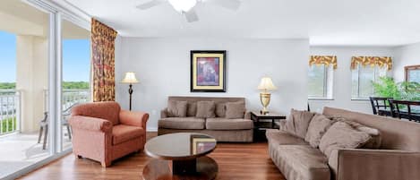 A spacious living room with a ceiling fan, two sofas, a coffee table, and a large window offering a view.