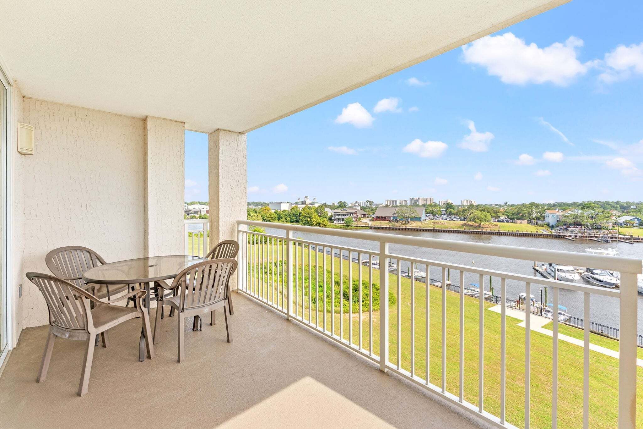 Een balkon met een tafel en stoelen, met uitzicht op een waterpartij met boten en gebouwen in de verte.