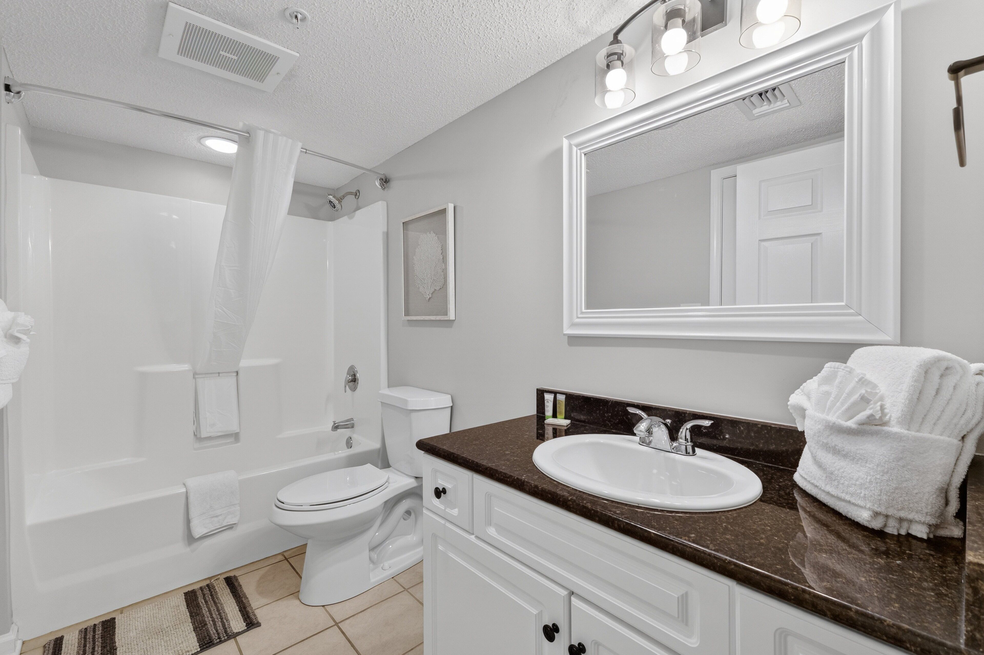 A modern bathroom with a bathtub, toilet, sink, and a large mirror.