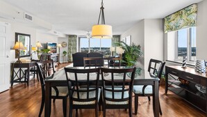 A spacious dining area with a large table and chairs, a hanging light fixture, and a view of the outdoors.