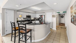 A modern kitchen with white cabinets, a central island, and a dining area with wooden chairs.