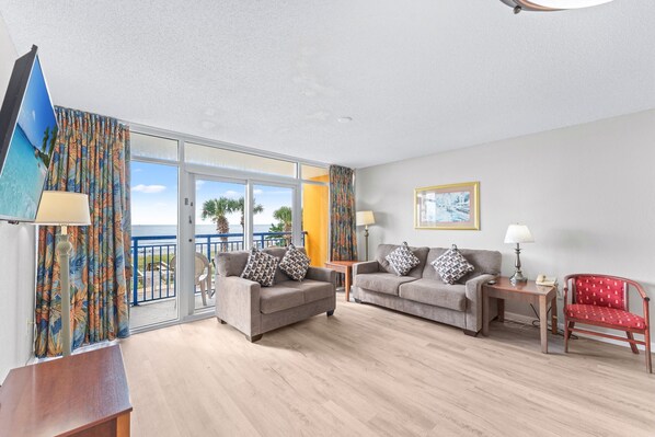 A modern living room with two sofas, a red chair, and a wooden table. - Atlantica 154, Beachfront Myrtle Beach Sping Retreat (Myrtle Beach)
