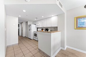 A modern kitchen with white cabinets, a granite countertop, and a built-in oven.