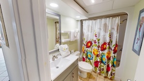 A bathroom with a toilet, sink, and shower curtain with floral patterns. - Atlantica 301, Oceanfront Myrtle Beach Condo Rental (Myrtle Beach)