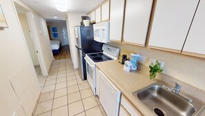 Una cocina compacta equipada con estufa, microondas, horno y pileta.
