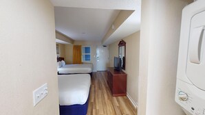 Habitación de hotel con dos camas, televisor, cómoda y puerta que da a otra habitación.