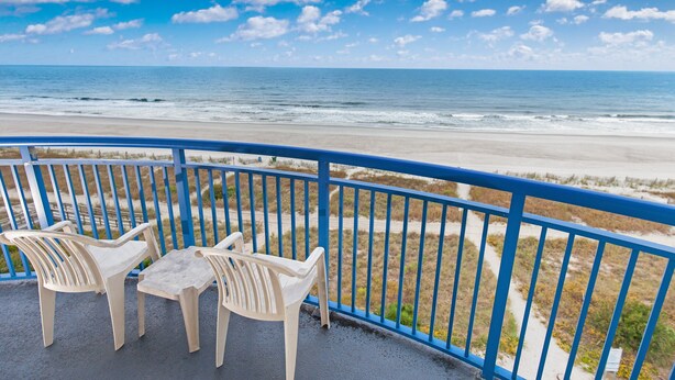 A balcony with a view of the beach and ocean.
