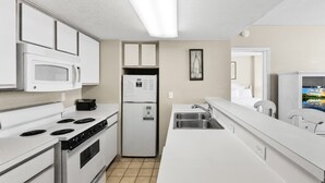 A modern kitchen with white cabinetry, a built-in microwave, a refrigerator, and a sink. - Atlantica 1202, Myrtle Beach Ocean Escape (Myrtle Beach)
