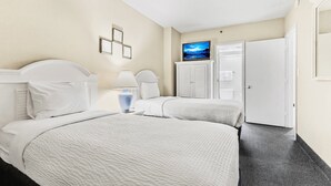 A hotel room with two beds, a TV, a wardrobe, and a door. - Atlantica 1202, Myrtle Beach Ocean Escape (Myrtle Beach)