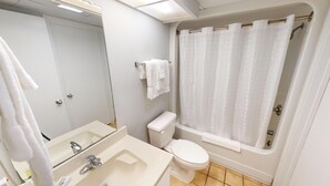 A bathroom with a sink, toilet, and bathtub with a shower curtain.
