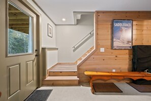 A staircase leading to a second floor, a wooden bench, a door with a window, and a poster on the wall. - Red Fox Lodge - Close to downtown Rangeley w/ Hot Tub & Sauna (Rangeley)