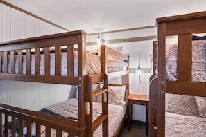 A bunk bed room with a wooden headboard, a bedside table, and a lamp. - Red Fox Lodge - Close to downtown Rangeley w/ Hot Tub & Sauna (Rangeley)