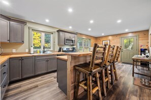 Een moderne keuken met grijze kastjes, een centraal eiland en houten stoelen.