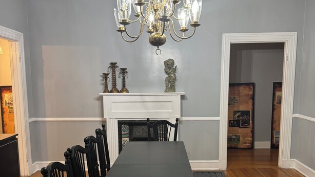 A dining room with a long table, black chairs, a chandelier, and a fireplace.