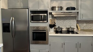 A modern kitchen with stainless steel appliances, including a refrigerator, microwave, oven, and stove. There are cabinets and a countertop with pots and pans.