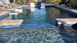 Un espace piscine avec une eau claire, des chaises longues et un patio abrité.