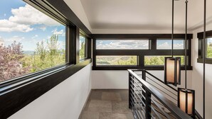 Ein modernes Interieur mit großen Fenstern, einer Treppe und Pendelleuchten.