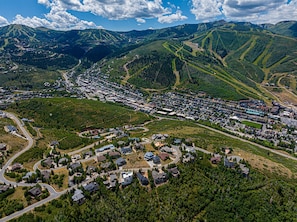 Vue aérienne d’une ville avec des rues sinueuses, des quartiers résidentiels et, au loin, un paysage montagneux.