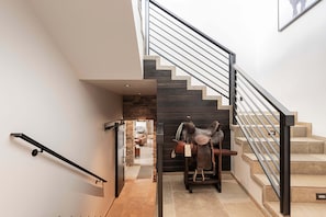 Un escalier moderne avec une rampe en métal, un mur en pierre et une selle en cuir accrochée au mur.