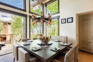 A dining area with a large table, chairs, a chandelier, and a stone fireplace. - Luxury Amongst the Aspens! Private Hot Tub 30-Day Rental (Park City)