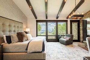 A bedroom with a large bed, a stone wall, and a view of the outdoors. - Luxury Amongst the Aspens! Private Hot Tub 30-Day Rental (Park City)