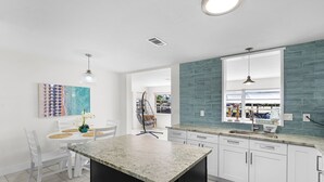 Una cocina moderna con armarios blancos, una encimera de granito y un salpicadero azul.