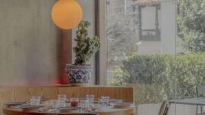 Comedor con mesa lista para cuatro personas, una planta en maceta y un colgador de luz.