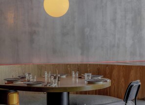Ein Restaurant mit einer Essecke in Holzvertäfelung, einer grauen Wand mit einer runden Leuchte und einem roten Neonlicht an der Decke.