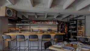 A bar area with stools, a bar counter, and a wine rack.