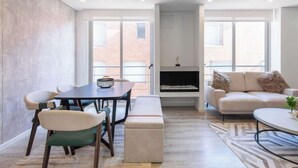 Ein modernes Wohnzimmer mit Essbereich, Kamin und großen Fenstern.