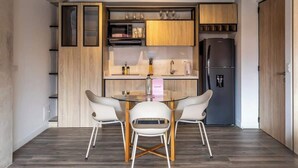 Eine kompakte Küche mit Essbereich, mit modernem Design, Holzschränken und einem Edelstahlkühlschrank.