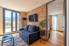A modern living room with a sofa, a flat-screen TV, a potted plant, and a sliding glass door leading to a balcony. - NOK Stylish 2 Masters w/Patio & View (Bogotá)
