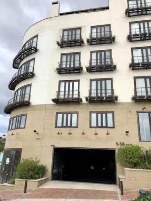Un edificio de varios pisos con balcones, entrada de garaje y diseño en esquina curva.