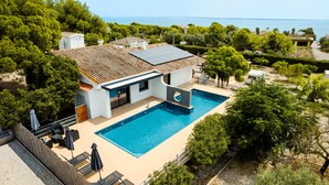 Uma casa moderna com piscina, painéis solares e vista para o mar.
