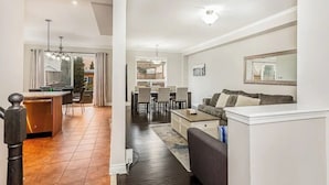 A modern living room with a sofa, coffee table, and a dining area with chairs and a table.