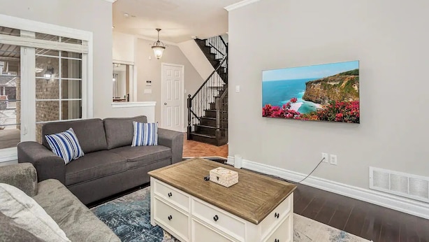A living room with a gray sofa, a coffee table, and a painting of a coastal landscape.