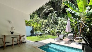 A modern indoor pool area with a tiled floor, a small table with chairs, and a seating area with a bench and chairs. - Charming 3-bedroom condo with pool, AC, WiFi in peaceful Herradura, pet friendly (Herradura)